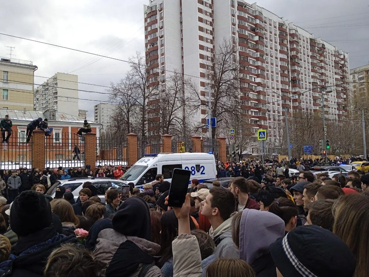 Сотрудники полиции оттесняют собравшихся от дороги.